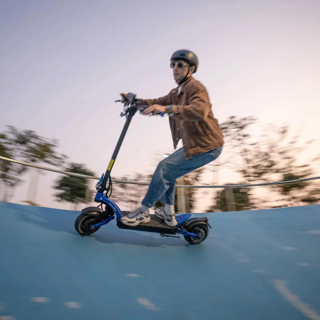 Oseba vozi električni skiro Kaabo Mantis X Plus na ukrivljeni rampi ob sončnem zahodu.
