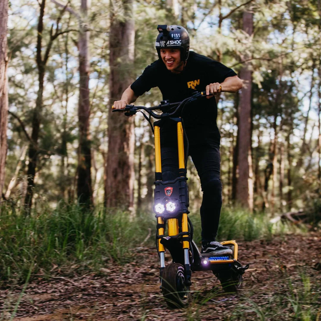 Oseba se vozi z električnim skirojem Kaabo Wolf King GT Pro po gozdni poti.