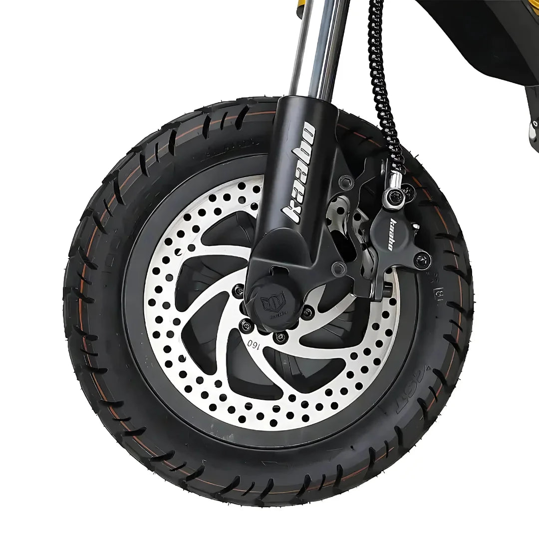 Izdelek je električni skiro, znamke Kaabo, model Wolf King GTR. Na sliki je prikazan sprednji kolesni del skiroja, ki vsebuje široko pnevmatiko z izrazitim profilom ter disk zavore z značilnim vzorcem. Vidna je tudi vilica, ki podpira kolo, kar kaže na robustno zasnovo skiroja, primernega za različne terenske pogoje.