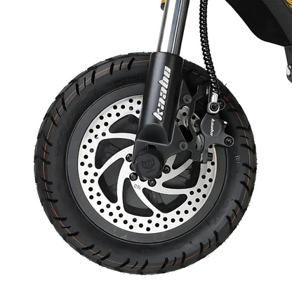 Izdelek je električni skiro, znamke Kaabo, model Wolf King GTR. Na sliki je prikazan sprednji kolesni del skiroja, ki vsebuje široko pnevmatiko z izrazitim profilom ter disk zavore z značilnim vzorcem. Vidna je tudi vilica, ki podpira kolo, kar kaže na robustno zasnovo skiroja, primernega za različne terenske pogoje.