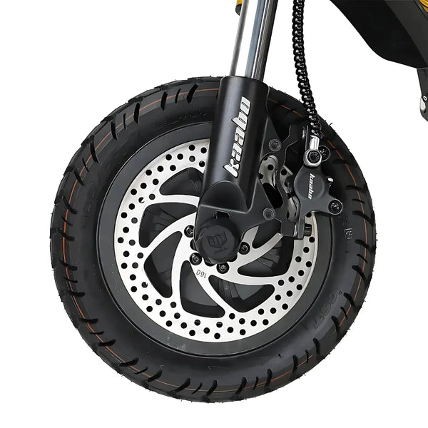 Izdelek je električni skiro, znamke Kaabo, model Wolf King GTR. Na sliki je prikazan sprednji kolesni del skiroja, ki vsebuje široko pnevmatiko z izrazitim profilom ter disk zavore z značilnim vzorcem. Vidna je tudi vilica, ki podpira kolo, kar kaže na robustno zasnovo skiroja, primernega za različne terenske pogoje.