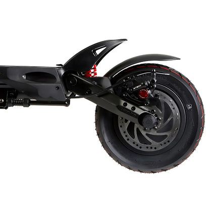 Izdelek na sliki je električni skiro, model Kaabo Mantis 10 Plus. Na sliki je prikazan zadnji del skiroja, vključno z zadnjim kolesom, vzmetenjem in zavorami. Kolo ima široko pnevmatiko z izrazitim profilom, kar nakazuje na dobro oprijemljivost, medtem ko je vzmetenje zasnovano za udobno vožnjo po različnih površinah.