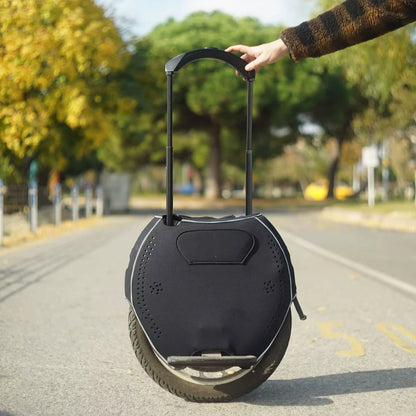 Oseba drži ročaj električnega monocikla Kingsong 18L na mirni ulici.