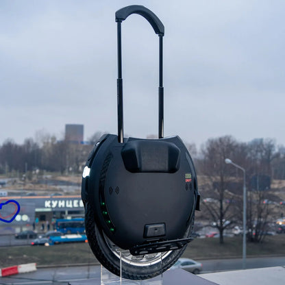 Električni monocikel Kingsong 18XL, prikazan na prostem z mestnim ozadjem.
