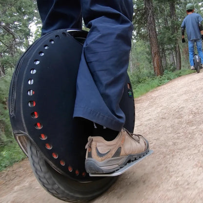 Oseba se vozi z električnim monociklom Kingsong 18xl po gozdni poti.