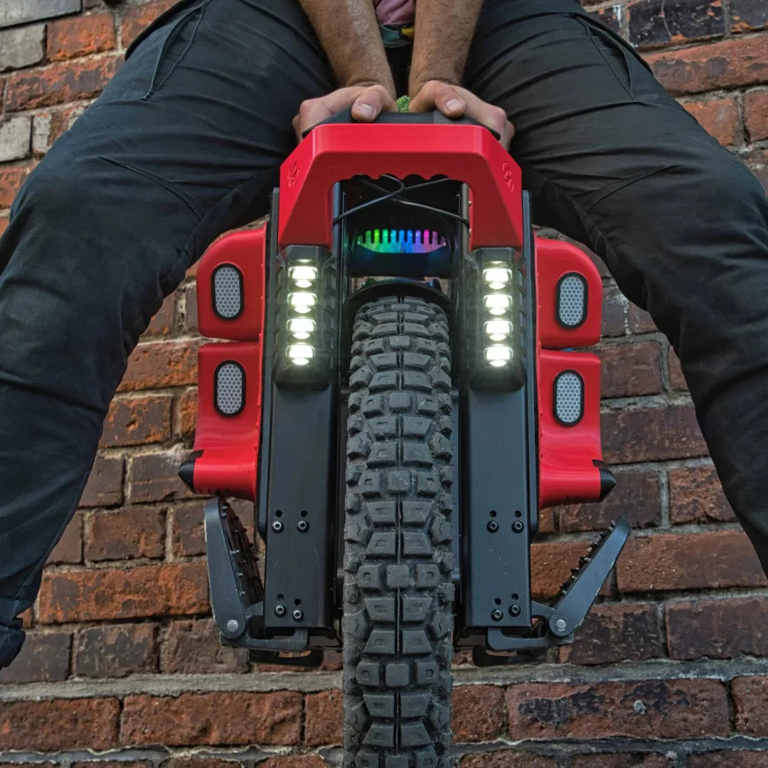 Izdelek na sliki je električni monocikel, model Kingsong S22 Pro. Na sliki je prikazan sprednji del monocikla, ki ima široko gumo z izrazitim profilom, kar nakazuje na njegovo sposobnost vožnje po različnih terenih. Vidni so tudi svetlobni elementi, ki dodajajo estetski videz in funkcionalnost, ter robustna konstrukcija, kar nakazuje na trajnost in zmogljivost.