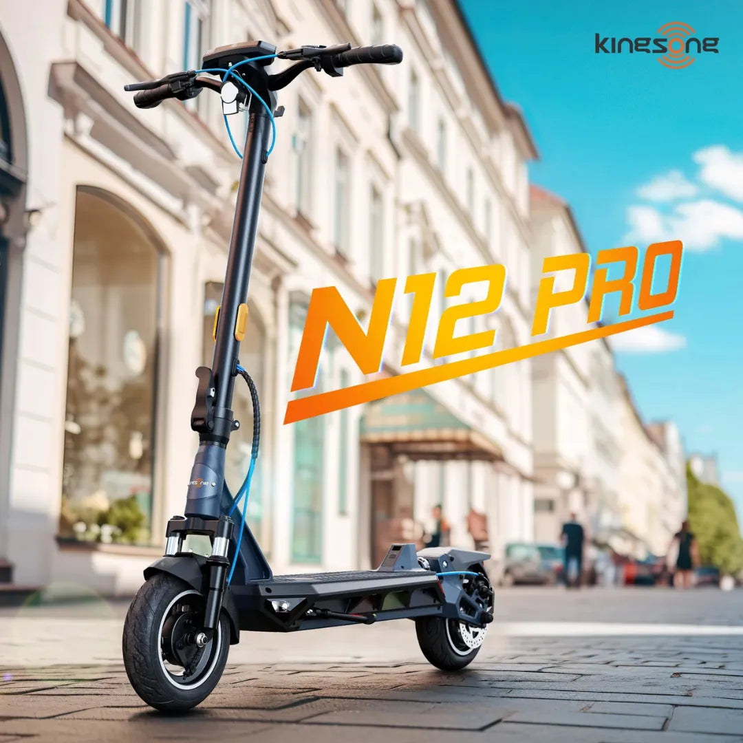 Na sliki je električni skiro znamke Kingsong, model N12 Pro. Vidimo ga postavljen na pločniku v mestnem okolju, kjer so v ozadju vidne stavbe in ulice. Skrbno oblikovan skiro ima široko platformo in robustne pnevmatike, kar nakazuje na njegovo zmogljivost in stabilnost pri vožnji. Roke skiroja so opremljene z ročaji za upravljanje.