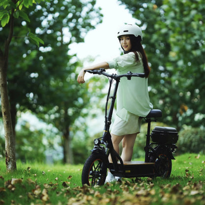 Na sliki je električni skiro znamke Kukirin, model C1 Pro. Predstavljen je v naravnem okolju, kjer mlada ženska stoji ob skiroju, oblečena v svetlo zeleno majico in kratke hlače. Na glavi nosi belo čelado za zaščito. Ozadje je zeleno, s številnimi drevesi in listjem, kar ustvarja prijetno in sproščeno vzdušje.