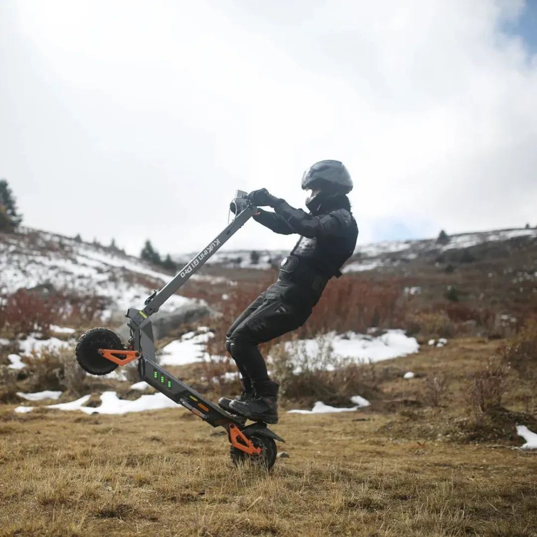 Voznik izvaja trik na električnem skiroju Kukirin G1 Pro v zasneženi pokrajini.
