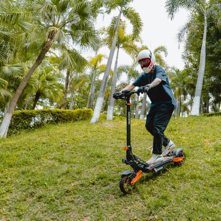 Oseba se vozi z električnim skirojem Kukirin G2 Max na travnatem hribu, obkroženem s palmami.