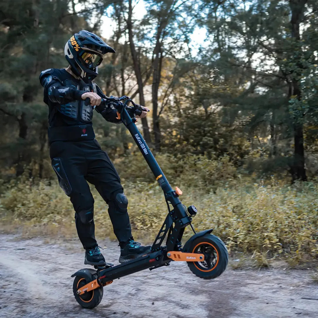 Voznik izvaja trik z električnim skirojem Kukirin G2 Max v gozdnatem območju.