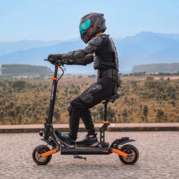Voznik z zaščitno opremo vozi električni skiro Kukirin G2 Pro po slikoviti cesti.