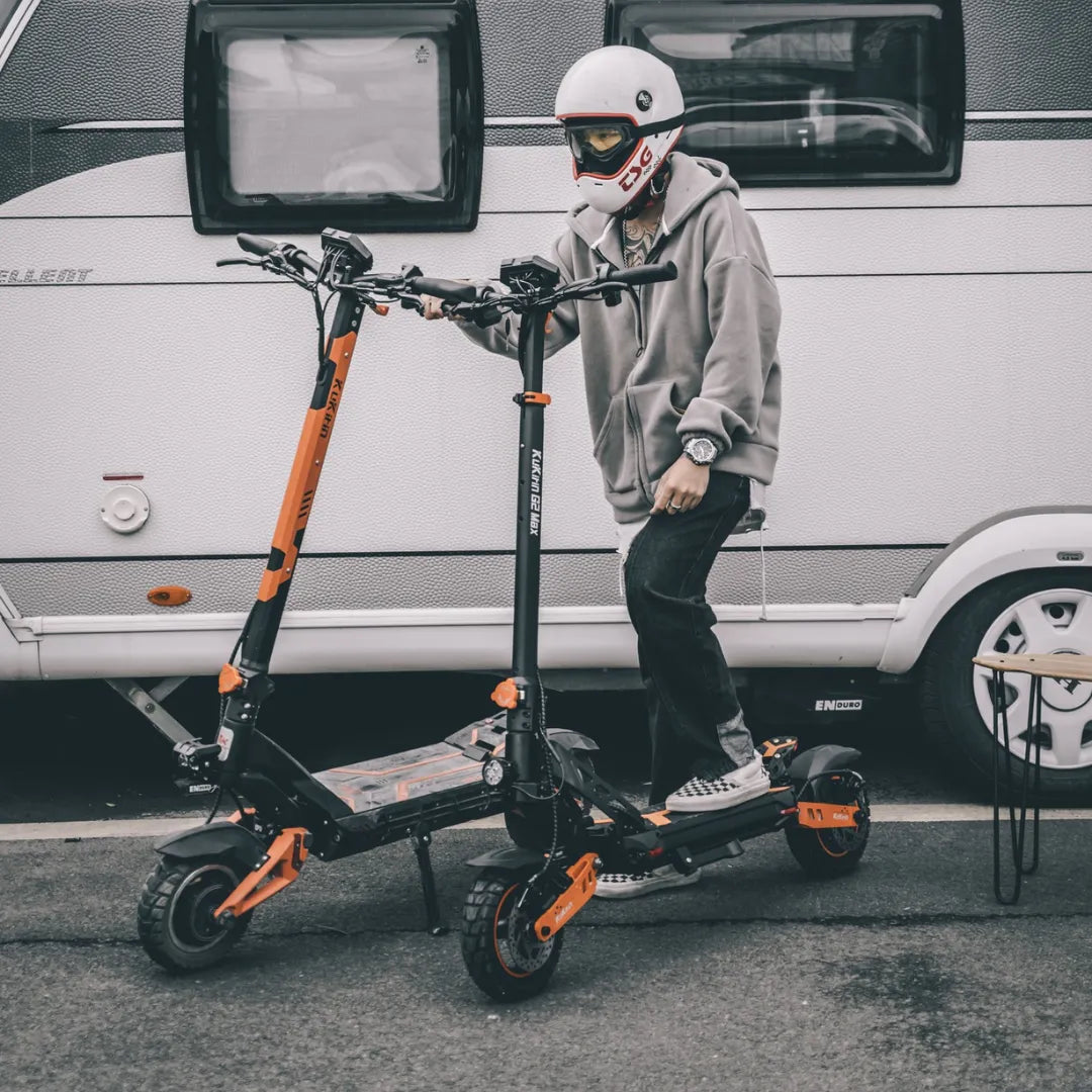 Oseba s čelado stoji ob dveh električnih skirojih Kukirin G3 Pro.