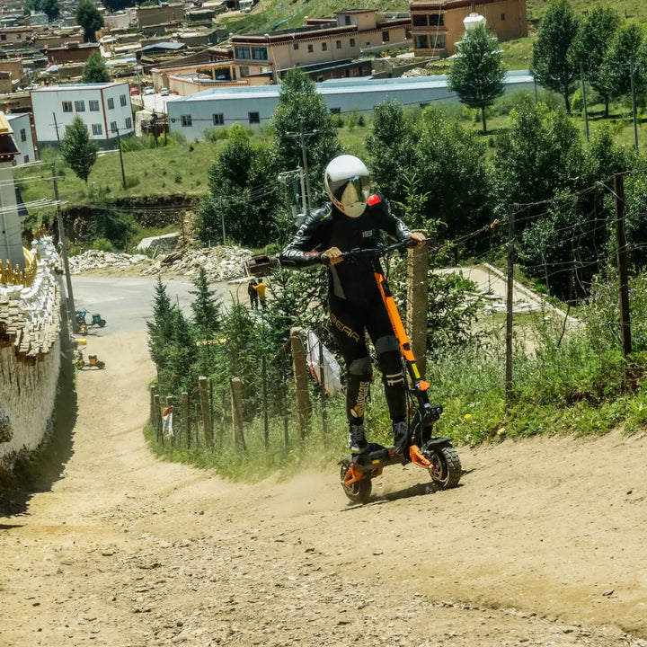 Voznik se spušča po makadamski poti z električnim skirojem Kukirin G3 Pro, obkrožen z zelenjem.