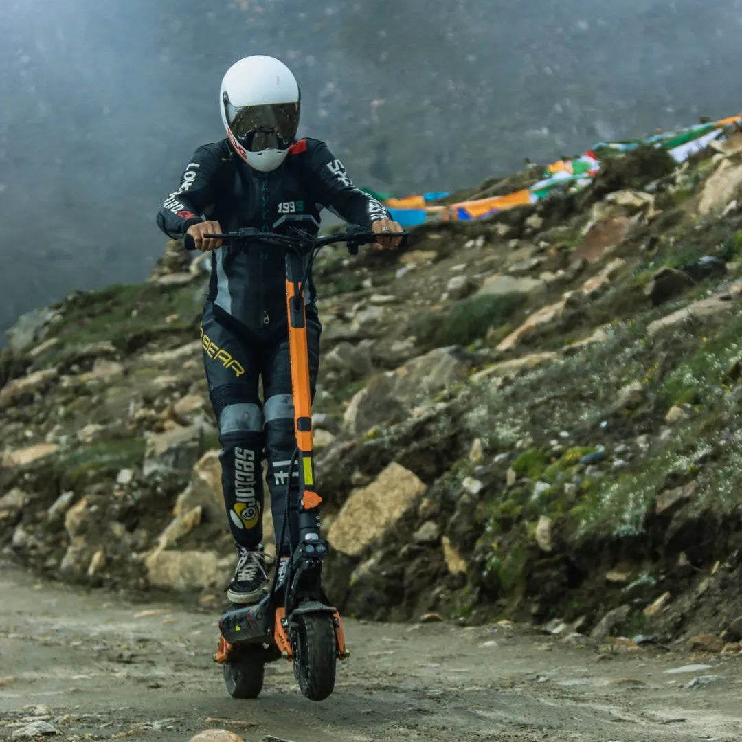Voznik električnega skiroja Kukirin G3 Pro se premika po razgibanem, skalnatem terenu.