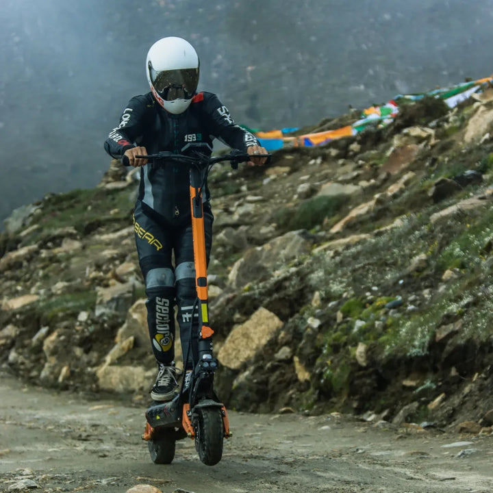 Voznik električnega skiroja Kukirin G3 Pro se premika po razgibanem, skalnatem terenu.
