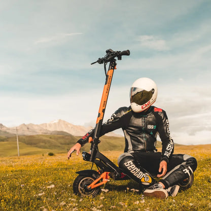 Jezdec s čelado sedi poleg električnega skiroja Kukirin G3 Pro na travnatem polju.