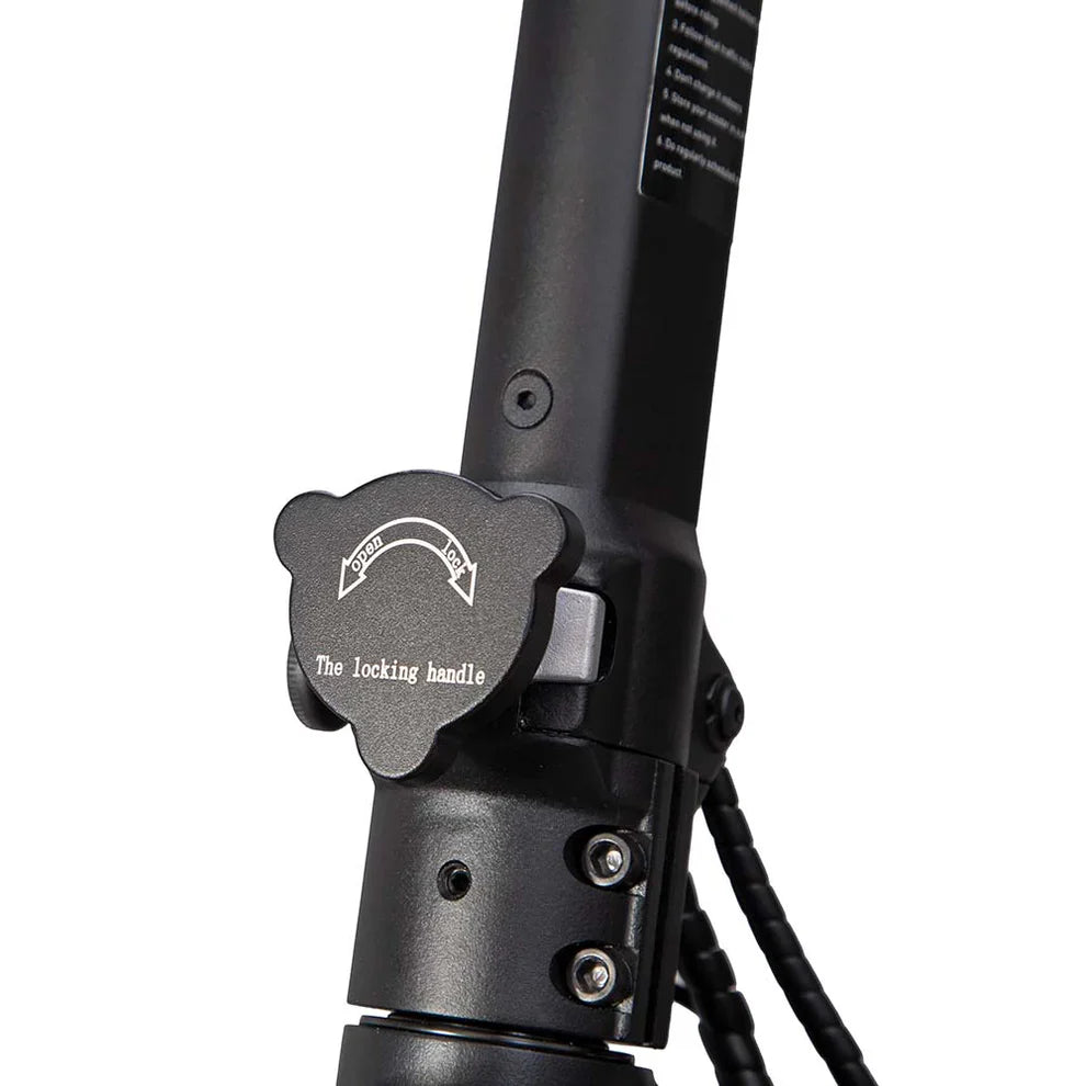 Izdelek je električni skiro, znamke Kukirin, model G2 Master. Na sliki je prikazan del skiroja, natančneje ročaj za zaklepanje, ki omogoča zlaganje ali odpiranje skiroja. Vidna je tudi črna barva materiala in nekateri detajli, kot so vijaki in oznake za uporabo.