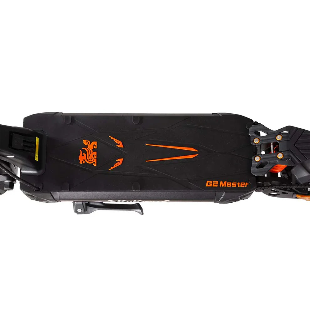 Izdelek je električni skiro, znamke Kukirin, model G2 Master. Na sliki je vidna zgornja površina skiroja, ki je v črni barvi z oranžnimi detajli. Površina ima teksturiran vzorec za boljši oprijem, ob robu pa je vidna tudi oznaka modela. Na eni strani je prikazan prostor za baterijo, kar nakazuje na električni pogon.