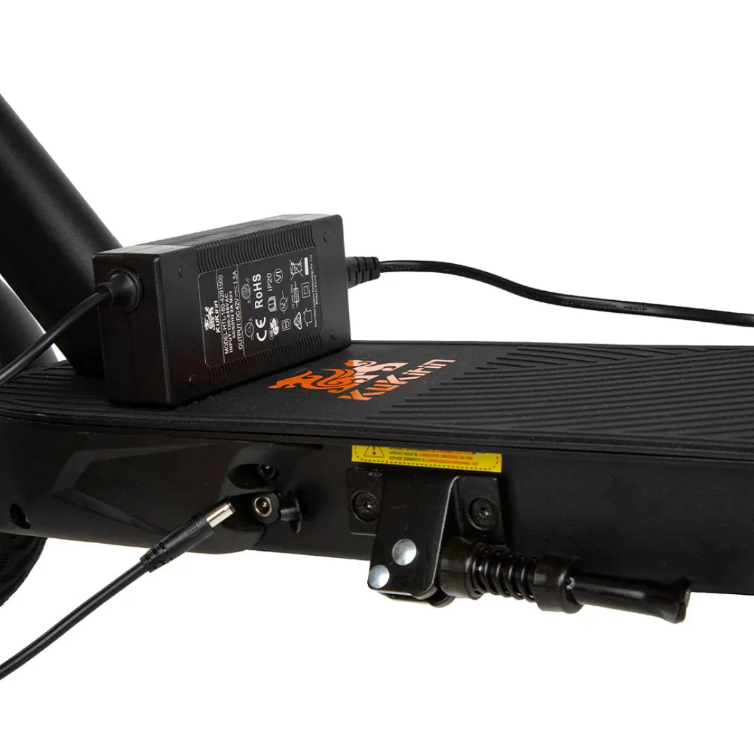 Na sliki je električni skiro znamke Kukirin, model S1 Max. Vidna je podlaga skiroja z oznako znamke, priključek za polnjenje ter polnilec, ki je povezan z napravo. Skiro ima robustno zasnovo in gumirano površino za boljši oprijem.