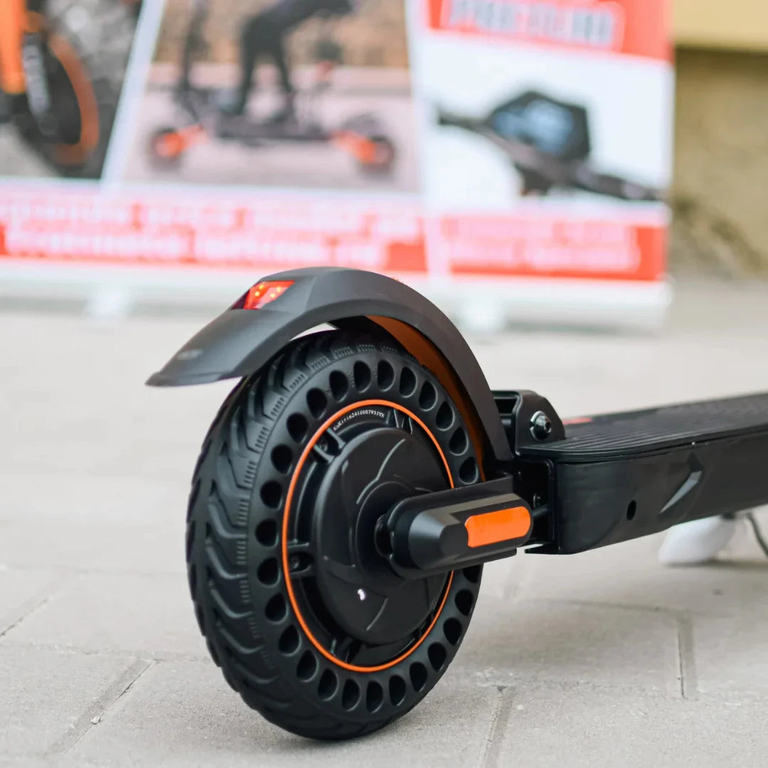 Izdelek na sliki je električni skiro, model Kukirin S1 Max. Vidna je zadnja kolesa skiroja z značilnim dizajnom, ki vključuje široko pnevmatiko z odprtinami za boljšo oprijemljivost. Na kolesu je tudi svetlobni indikator, kar povečuje varnost pri vožnji. V ozadju so prikazane promocijske slike, ki dodatno predstavljajo ta model.