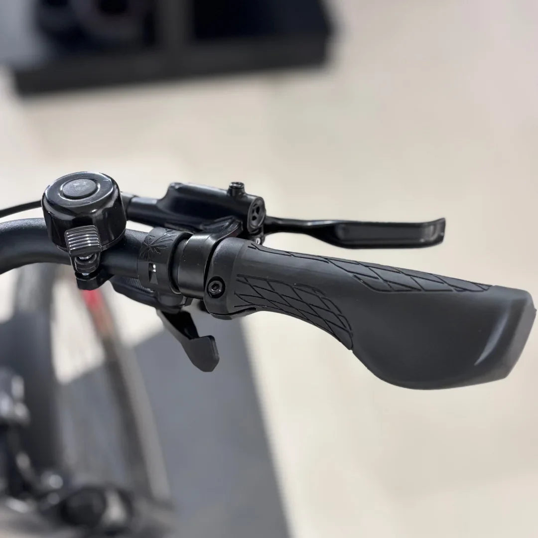 Izdelek je električno kolo znamke Malaguti, model Bolonina. Na sliki je prikazan del krmila, ki vključuje ročico za zaviranje, ročaj in zvonec. Ročaji so oblikovani za udoben oprijem, kar omogoča boljšo kontrolo med vožnjo.