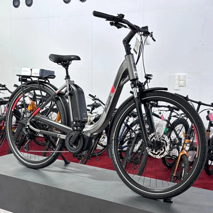 Izdelek na sliki je električno kolo znamke Malaguti, model Bolonina. Kolo ima sodobno obliko s širokimi pnevmatikami in električnim motorjem, ki je nameščen na okvirju. Na zadnjem delu se nahaja baterija, ki omogoča električni pogon. Kolo je postavljeno na stojalo, v ozadju pa so vidna tudi druga kolesa.