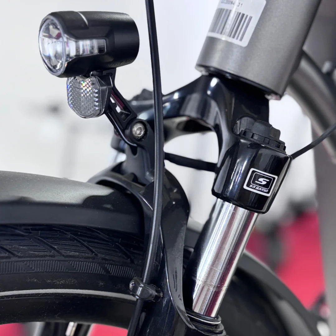 Izdelek na sliki je električno kolo znamke Malaguti, model Bolonina. Na sliki je prikazan del sprednjega vzmetenja, ki vključuje svetilko in del prednje vilice. Vidna je tudi pnevmatika s profilom, ki je primeren za različne vrste terena. Kolo je zasnovano za udobno in varno vožnjo.