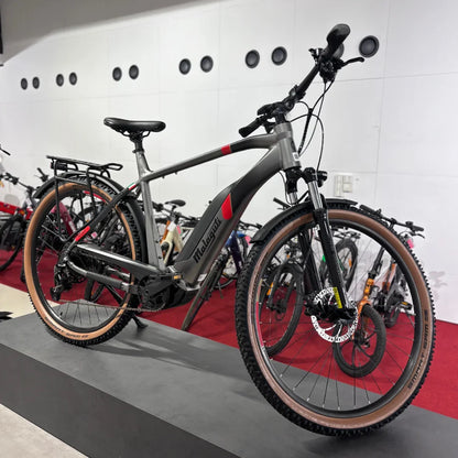 Na sliki je električno kolo znamke Malaguti, model Carezza TR 4.0. Kolo ima robustno zasnovo z močnim okvirjem in širokimi gumami, kar nakazuje na primernost za različne terene. Vidni so tudi dodatki, kot so nosilec za prtljago in disk zavore, kar povečuje funkcionalnost in varnost pri vožnji. Kolo je postavljeno na podstavek v prodajnem prostoru, kjer so v ozadju vidna tudi druga kolesa.