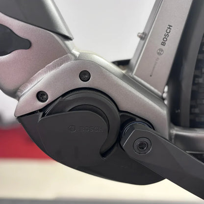 Izdelek je električno kolo, model Malaguti Carezza TR 4.0 High Step. Na sliki je prikazan del kolesa, ki vključuje motor Bosch, kar nakazuje na kakovostno električno asistenco. Vidni so tudi detajli okvirja in mehanizma, kar kaže na robustno konstrukcijo in sodobno tehnologijo.