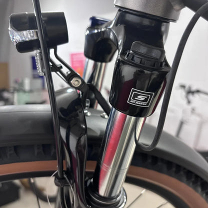 Izdelek je električno kolo, znamke Malaguti, model Carezza TR 4.0 High Step. Na sliki je prikazan del sprednjega vzmetenja, ki vključuje vilice in svetilko. Vidna je tudi povezava kablov in nekateri detajli na okvirju, kar nakazuje na kakovostno izdelavo in funkcionalnost kolesa.