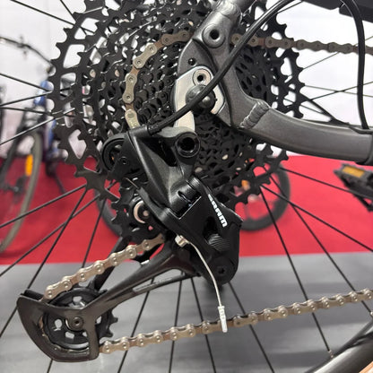 Na sliki je električno kolo znamke Malaguti, model Carezza TR 4.0 High Step. Prikazan je del zadnjega menjalnika, ki vključuje verigo in kaseto. Oprema je zasnovana za učinkovito prestavljanje, kar je ključno za zmogljivost kolesa. V ozadju so vidni tudi drugi kolesi, kar nakazuje na okolje, v katerem je izdelek razstavljen.