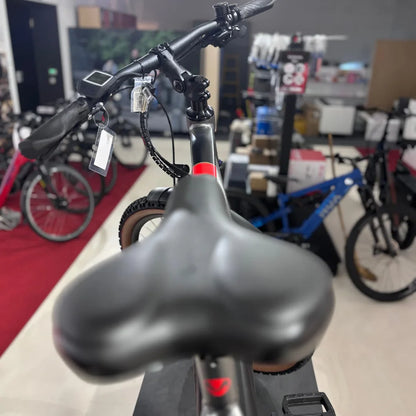 Izdelek na sliki je električno kolo znamke Malaguti, model Carezza TR 4.0 s visokim korakom. Na sliki je vidna sprednja stran kolesa, vključno s krmilom, sedežem in delom okvirja. V ozadju so tudi drugi kolesi, kar nakazuje, da gre za trgovino s kolesi.