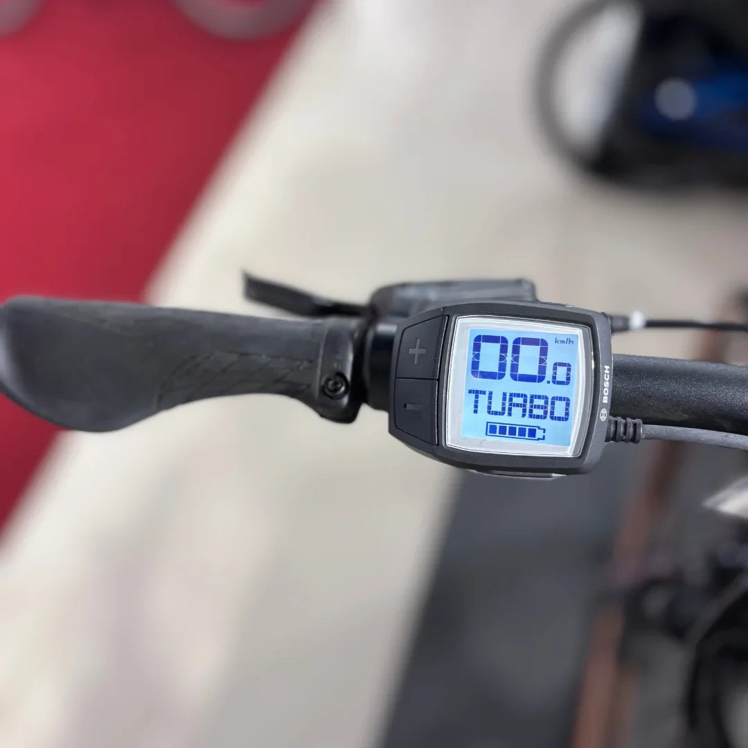 Izdelek na sliki je električno kolo, znamke Malaguti, model Carezza TR 4.0. Na sliki je prikazan del krmila, kjer je nameščen digitalni zaslon, ki prikazuje hitrost (0 km/h) in način vožnje (Turbo). Zaslon je opremljen z gumbi za prilagajanje nastavitev.