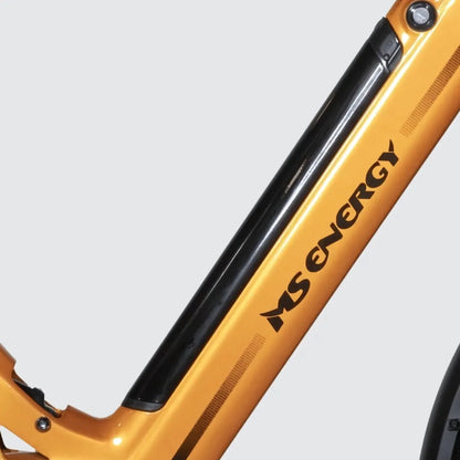 Izdelek je električno kolo, znamke MS Energy, model SUV C502. Na sliki je del okvirja kolesa, ki je v svetlo oranžni barvi, z vidnim napisom "MS ENERGY". Na okvirju je tudi črn del, ki verjetno predstavlja baterijo ali prostor za baterijo. Kolo ima sodoben in športen videz, kar nakazuje na njegovo uporabnost v različnih terenih.