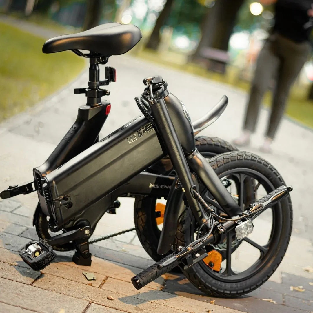 Izdelek na sliki je električno kolo, model MS Energy Urbanfold i6. Kolo je zložljivo, kar omogoča enostavno prenašanje in shranjevanje. Na sliki so vidni sedež, zloženi okvir ter kolesa, ki so opremljena z debelimi pnevmatikami. Kolo ima tudi električni motor in baterijo, kar je značilno za električna kolesa. Celotna zasnova je kompaktna in moderna, kar je primerno za urbano okolje.