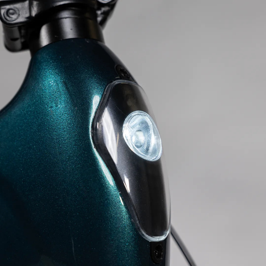 Izdelek je električno kolo, znamke MS Energy, model Urbanfold i6. Na sliki je vidna podrobnost okvirja kolesa v temno zeleni barvi s svetlom, ki je nameščeno na sprednjem delu. Svetloba je zasnovana za izboljšanje vidljivosti in varnosti med vožnjo.