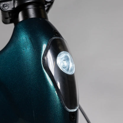 Izdelek je električno kolo, znamke MS Energy, model Urbanfold i6. Na sliki je vidna podrobnost okvirja kolesa v temno zeleni barvi s svetlom, ki je nameščeno na sprednjem delu. Svetloba je zasnovana za izboljšanje vidljivosti in varnosti med vožnjo.