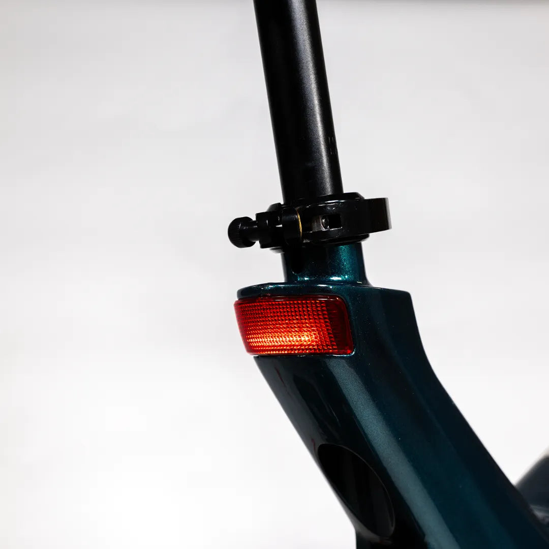 Izdelek je električno kolo, model MS Energy Urbanfold i6. Na sliki je prikazan del okvirja kolesa, kjer je vidna zadnja lučka in povezovalni element med okvirjem in sedežem. Barva okvirja je temno zelena, kar daje kolesu sodoben videz.