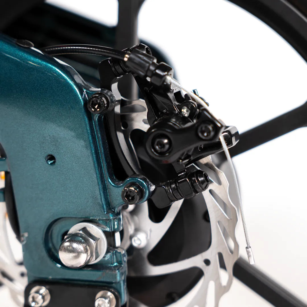 Izdelek je električno kolo, znamke MS Energy, model Urbanfold i6. Na sliki je prikazan del kolesa, natančneje zavorni sistem, ki vključuje disk in mehanizem za zaviranje. Vidna je tudi struktura okvirja, ki ima modro barvo, kar daje kolesu sodoben in atraktiven videz.