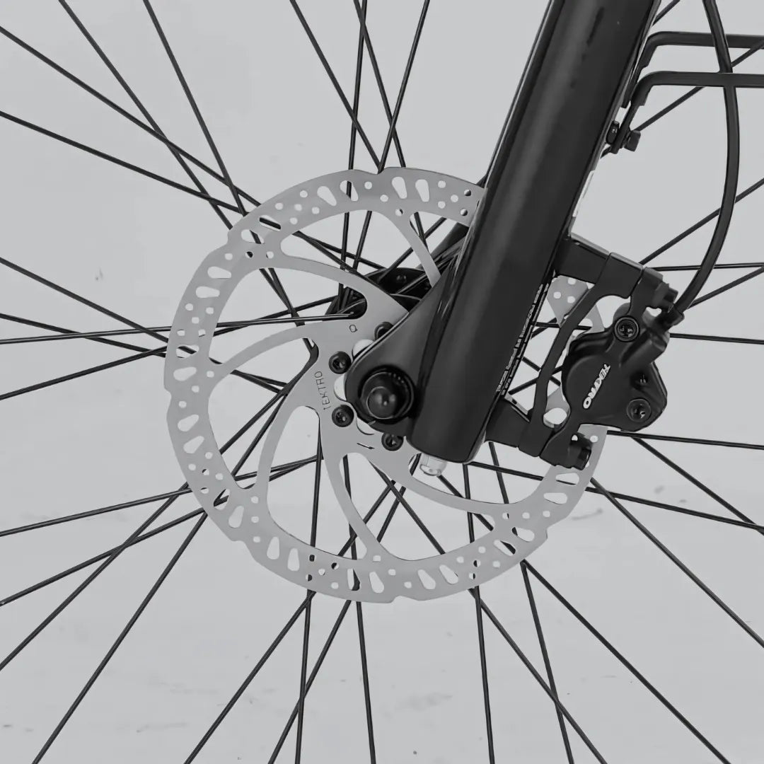 Izdelek je električno kolo, model MS Energy C300. Na sliki je prikazan del sprednjega kolesa z disk zavornim sistemom. Vidna je zavora, ki vključuje zavornico in rotor, kar nakazuje na sodobno tehnologijo zaviranja, ki zagotavlja učinkovito in varno ustavljanje. Kolo ima tudi črno barvo okvirja in druge komponente.