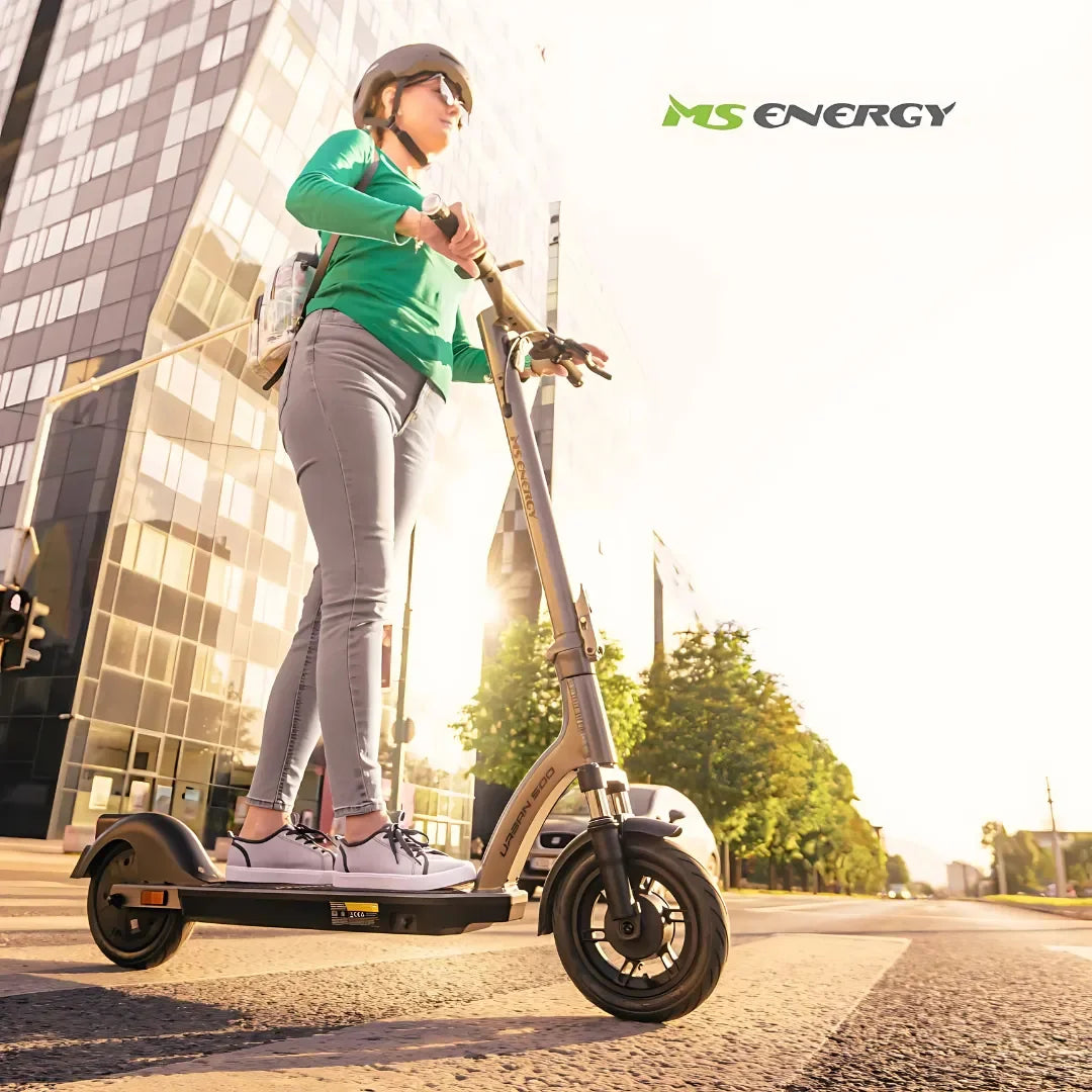 Oseba se vozi z električnim skirojem Ms Energy Urban 500 po sončni mestni ulici.