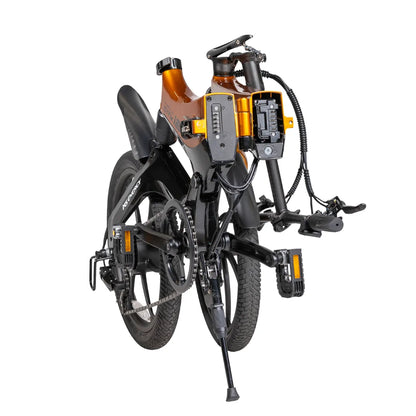 Izdelek na sliki je električno kolo, model MS Energy i20. Kolo je zloženo, kar je razvidno iz njegove kompaktne oblike. Na sliki so vidne tudi komponente, kot so baterija in krmilna enota, ki sta nameščeni na okvirju. Barvna kombinacija vključuje črno in oranžno, kar daje kolesu sodoben videz.