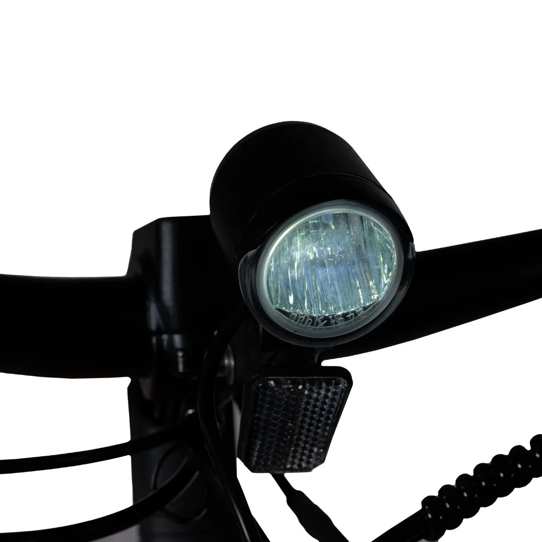 Izdelek je električno kolo, model MS Energy SUV C502. Na sliki je prikazan del krmila, ki vključuje svetilko in odsevnike. Svetilka je nameščena na sprednjem delu, kar omogoča boljšo vidljivost med vožnjo, medtem ko odsevniki povečujejo varnost v temi. Celoten dizajn je funkcionalen in praktičen za urbano vožnjo.