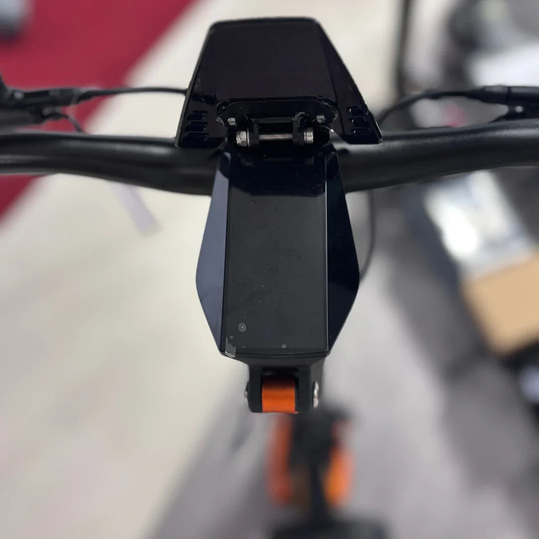 Izdelek na sliki je električni skiro, model MS Energy Flare X Pro. Na sliki je vidna zgornja plošča krmila, ki vključuje zaslon in gumb za upravljanje. Barvna kombinacija vključuje črne in oranžne detajle, kar daje skiroju športen videz. V ozadju so vidni deli skiroja in okolica, kar nakazuje na prodajno mesto.