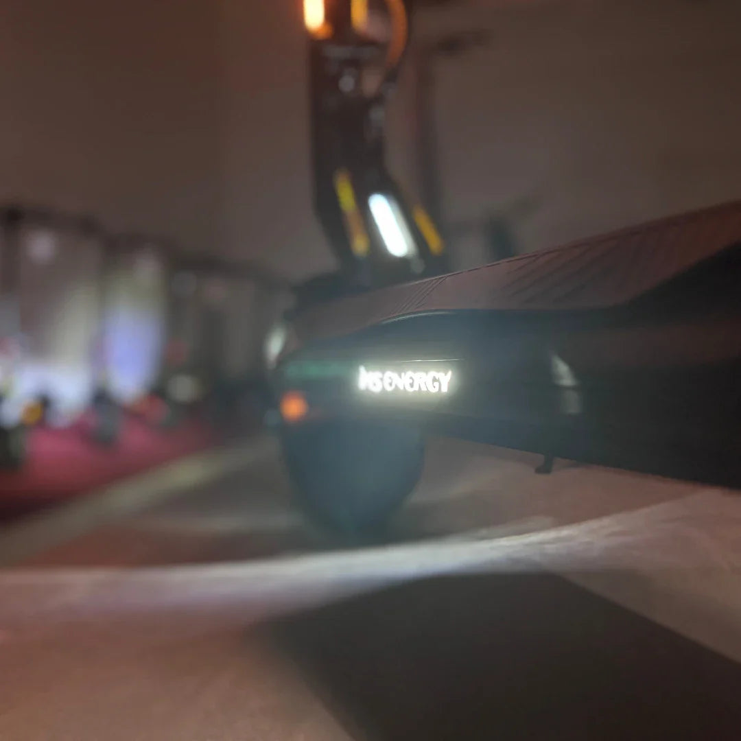 Izdelek na sliki je električni skiro, model MS Energy Flare X Pro. Na sliki je vidna osnova skiroja z izpostavljenim logotipom "MS ENERGY", ki sveti. Ozadje je nekoliko zamegljeno, kar daje občutek dinamike in sodobnosti. Skupaj z obliko in detajli skiroja nakazuje na njegovo funkcionalnost in stil.