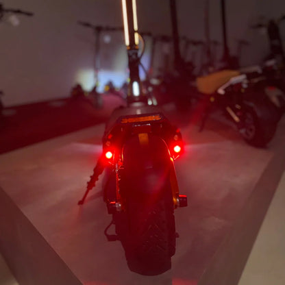 Izdelek na sliki je električni skiro, model MS Energy Flare X Pro. Na sliki je prikazan zadnji del skiroja, ki ima rdeče luči in robustne pnevmatike, kar nakazuje na njegovo zmogljivost in varnost pri vožnji. V ozadju so vidni tudi drugi skiroji, kar ustvarja občutek razstave.