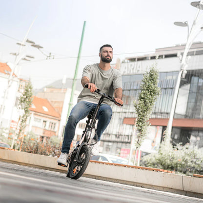 Izdelek na sliki je električno kolo, model MS Energy Urbanfold i6. Na sliki je moški, ki se vozi na tem električnem kolesu v urbanem okolju. Kolo ima kompakten in zložljiv dizajn, kar je primerno za mestno vožnjo. V ozadju so vidne moderne stavbe in mestna infrastruktura.