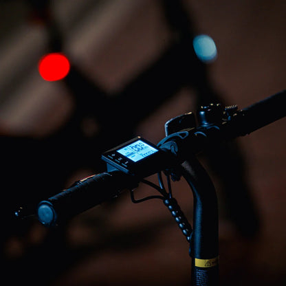 Izdelek je električno kolo, model MS Energy Urbanfold i6. Na sliki je vidna krmilo z digitalnim zaslonom, ki prikazuje hitrost in druge podatke. Zaslon je osvetljen, kar omogoča enostavno branje tudi v slabših svetlobnih pogojih, v ozadju pa so vidne tudi luči, kar nakazuje na nočno vožnjo.