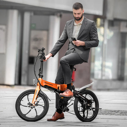 Izdelek na sliki je električno kolo, model MS Energy i20. Na sliki je moški v poslovnem obleku, ki sedi na kolesu in uporablja mobilni telefon. Kolo ima moderno zasnovo v oranžni barvi, z manjšimi kolesi, kar ga naredi primerno za urbano uporabo. V ozadju so mestni elementi, kar nakazuje, da je kolo namenjeno za vožnjo po mestnih ulicah.